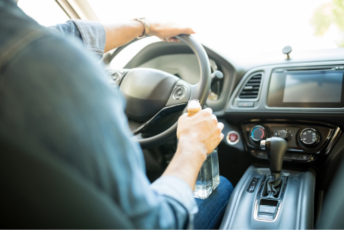 a man driving a car while drinking alcohol