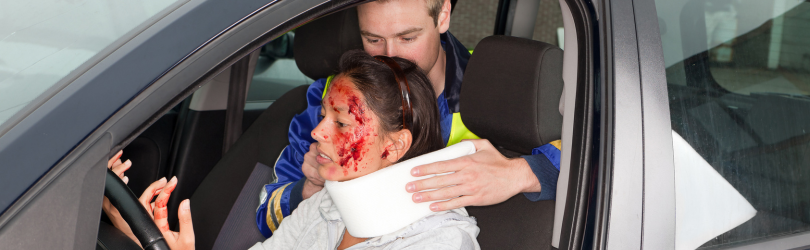 injured woman in a car crash getting a whiplash neck brace from the rescuer